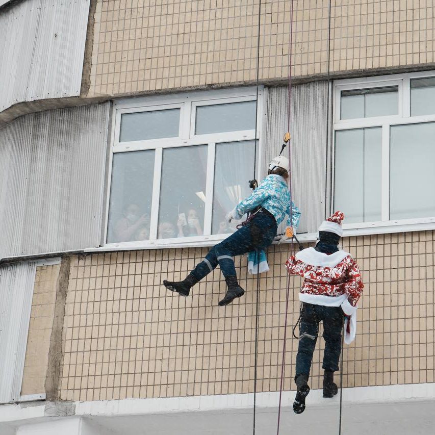 Добровольцы-спасатели спустились с крыши здания в костюмах Дедов Морозов и Снегурочек