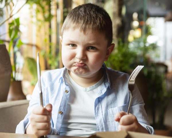 medium-shot-sad-kid-with-cutlery